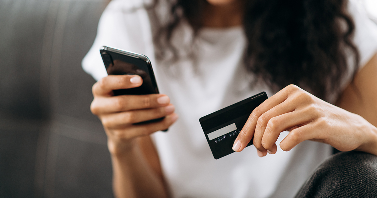 Woman using her cell phone while holding a credit card - in-app shopping